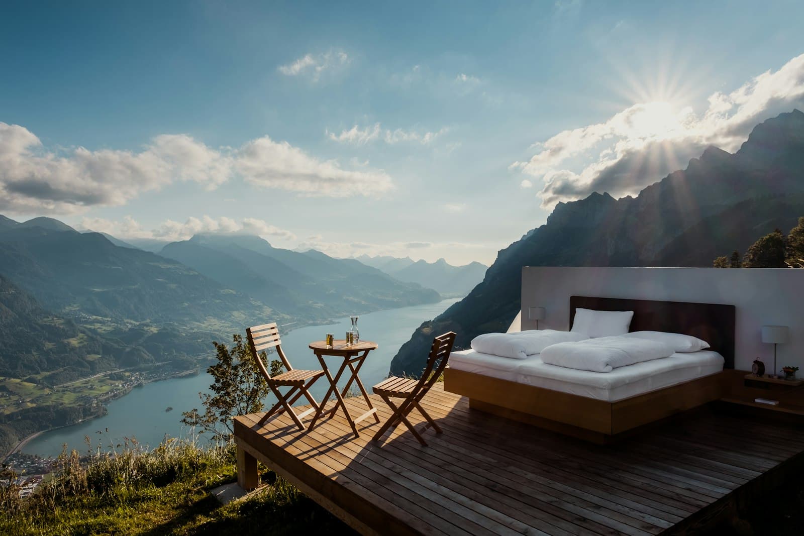 A bed facing an open balcony that looks straight onto forested mountains