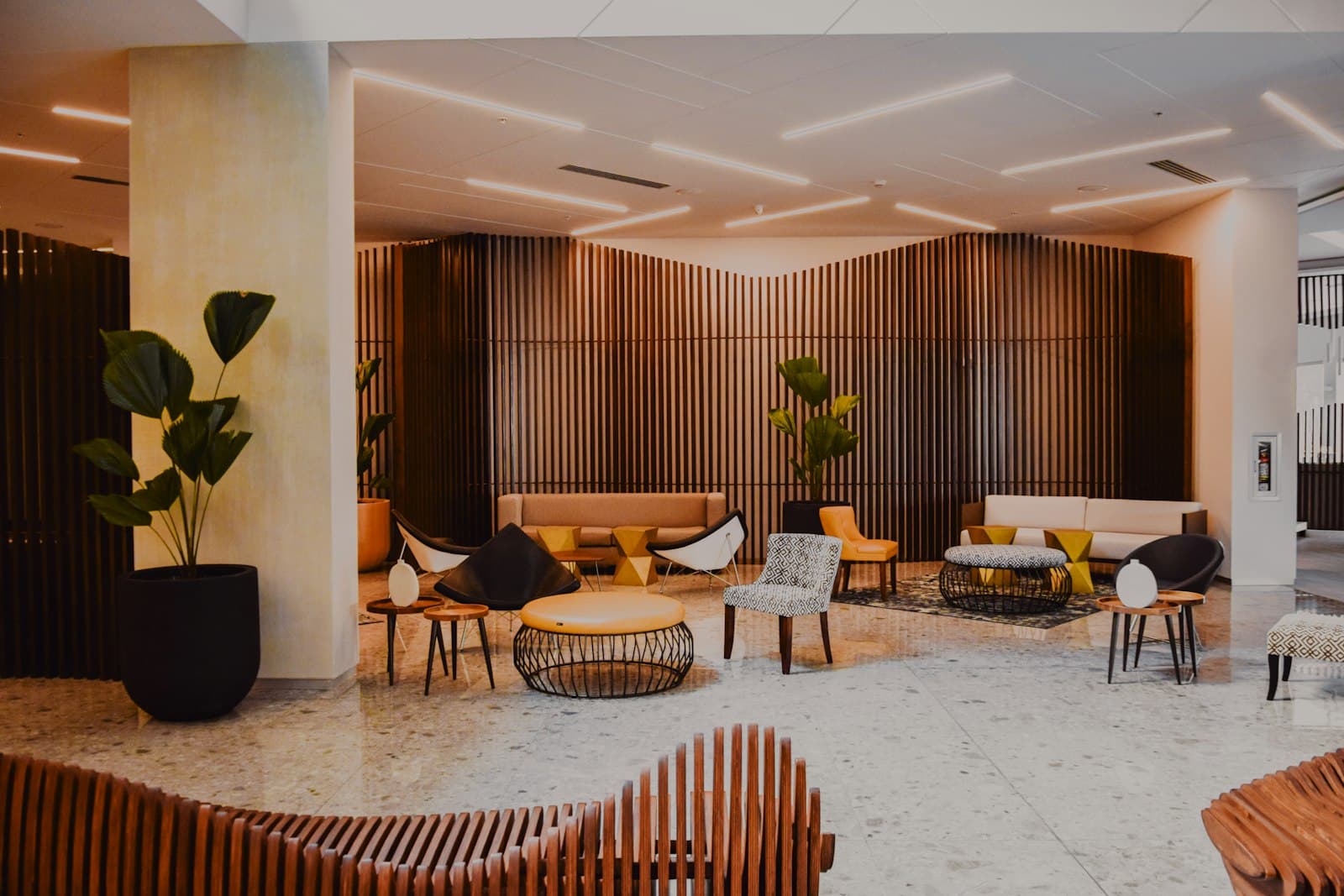 A warmly lit hotel lobby with curved timber panelling and low seating