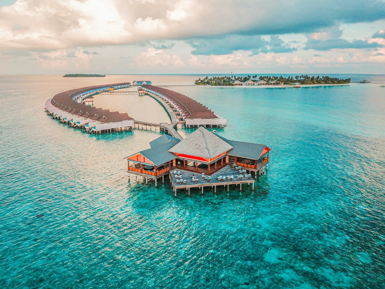 Aerial view of overwater bungalows arranged in an arc over a coral lagoon