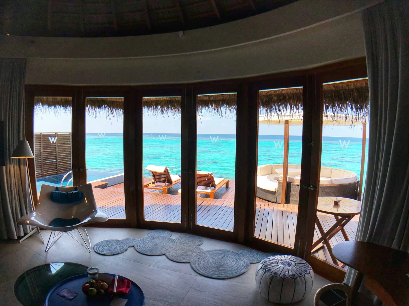 A villa living room with floor-to-ceiling windows opening onto the beach
